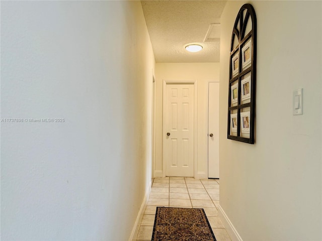 hall featuring a textured ceiling and light tile patterned flooring