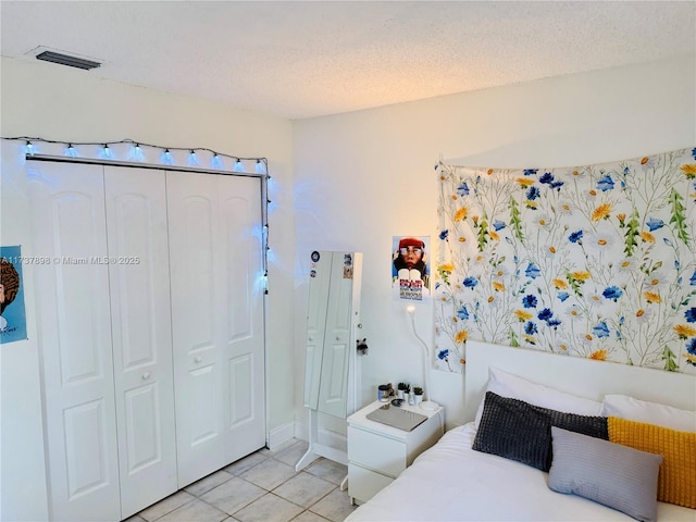 bedroom featuring light tile patterned floors, a textured ceiling, and a closet