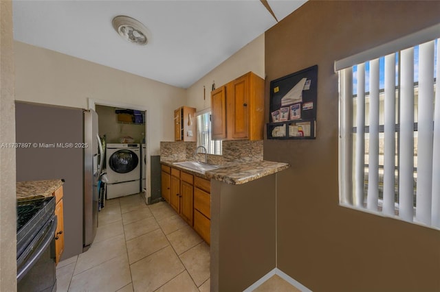 kitchen featuring washing machine and clothes dryer, sink, tasteful backsplash, range, and light tile patterned floors