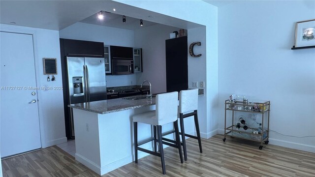 kitchen with sink, light hardwood / wood-style flooring, appliances with stainless steel finishes, a kitchen bar, and kitchen peninsula