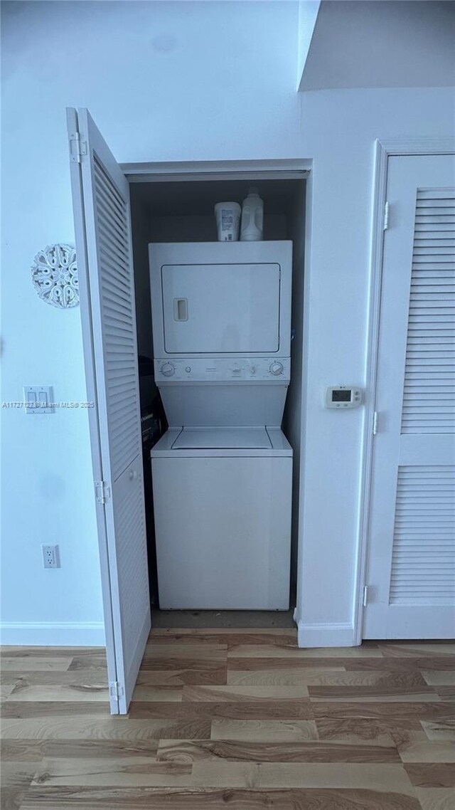 washroom with stacked washer and dryer and light hardwood / wood-style floors