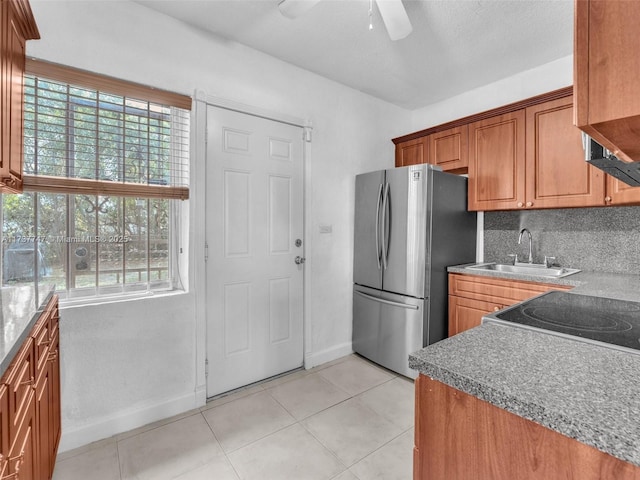 kitchen featuring sink, a wealth of natural light, stainless steel refrigerator, and decorative backsplash