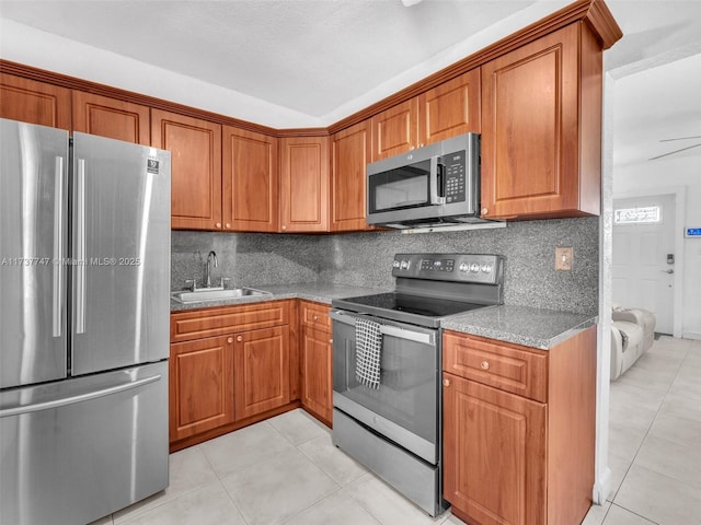 kitchen with light stone counters, decorative backsplash, light tile patterned flooring, and appliances with stainless steel finishes