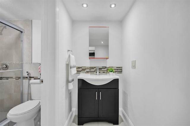 bathroom with a shower with door, vanity, backsplash, and toilet