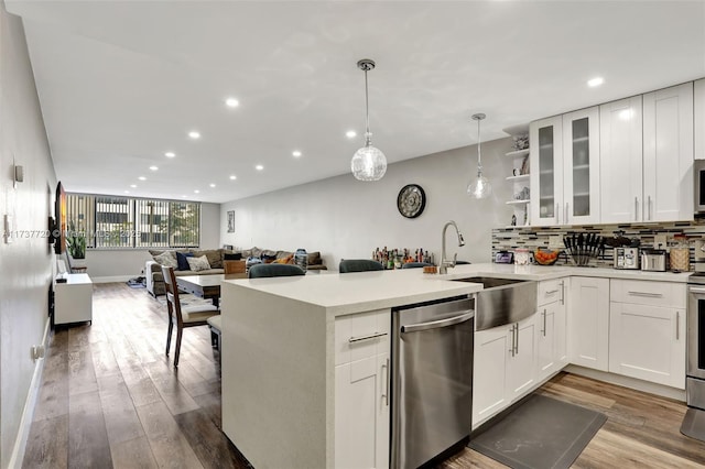 kitchen with light hardwood / wood-style flooring, appliances with stainless steel finishes, hanging light fixtures, white cabinets, and kitchen peninsula