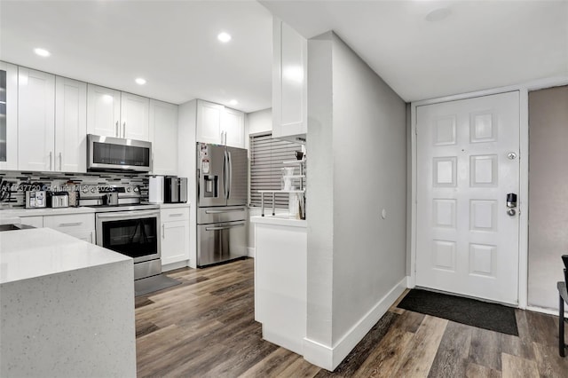 kitchen featuring white cabinetry, decorative backsplash, stainless steel appliances, and dark hardwood / wood-style floors