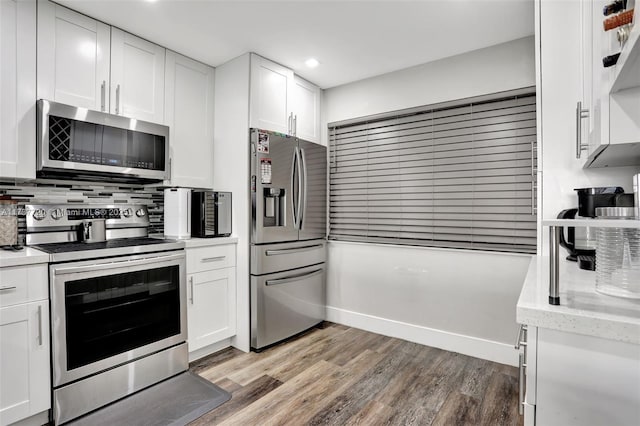 kitchen with appliances with stainless steel finishes, backsplash, white cabinets, light hardwood / wood-style floors, and light stone countertops