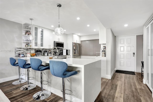 kitchen with pendant lighting, stainless steel appliances, dark hardwood / wood-style floors, and white cabinets