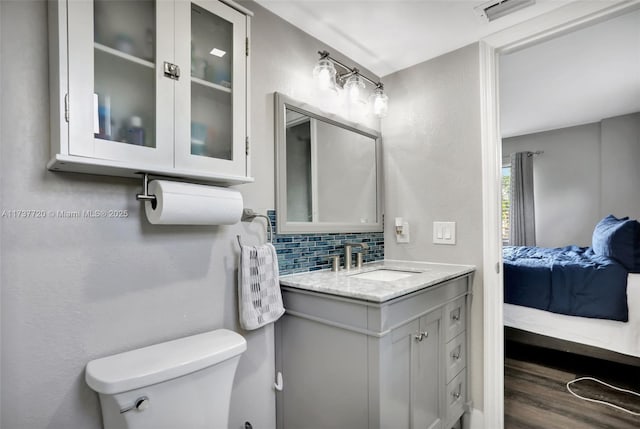 bathroom featuring vanity, hardwood / wood-style floors, decorative backsplash, and toilet