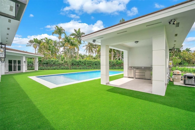 view of pool with a yard, a patio, and exterior kitchen