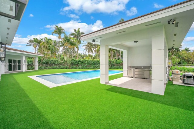 view of swimming pool with a yard, a patio area, and exterior kitchen