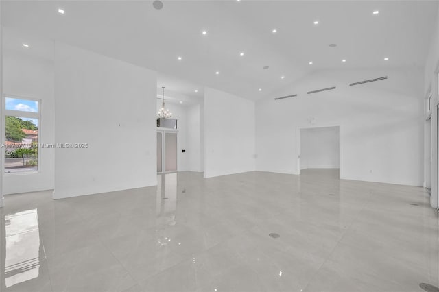 spare room featuring an inviting chandelier and high vaulted ceiling