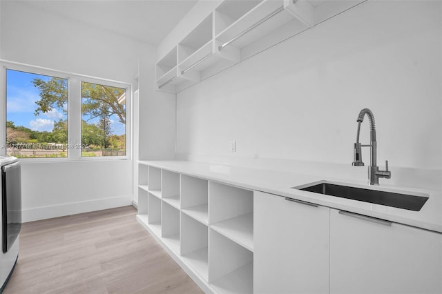 spacious closet with separate washer and dryer, sink, and light wood-type flooring