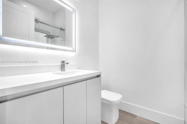 bathroom featuring vanity, hardwood / wood-style floors, a shower with door, and toilet