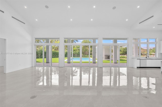 unfurnished living room with sink and a towering ceiling