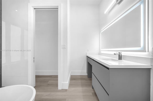 bathroom featuring vanity, hardwood / wood-style floors, and a tub to relax in