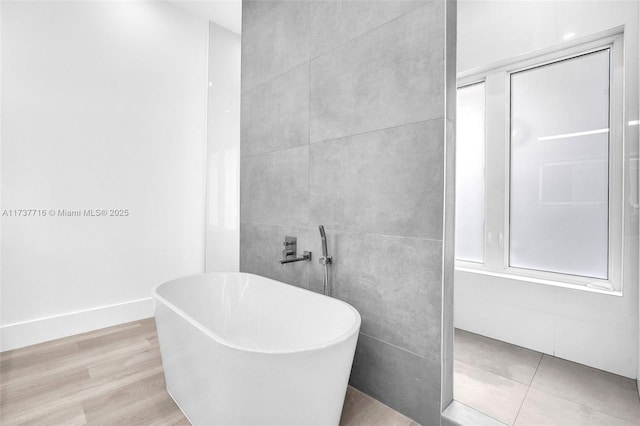 bathroom featuring hardwood / wood-style floors and a tub to relax in