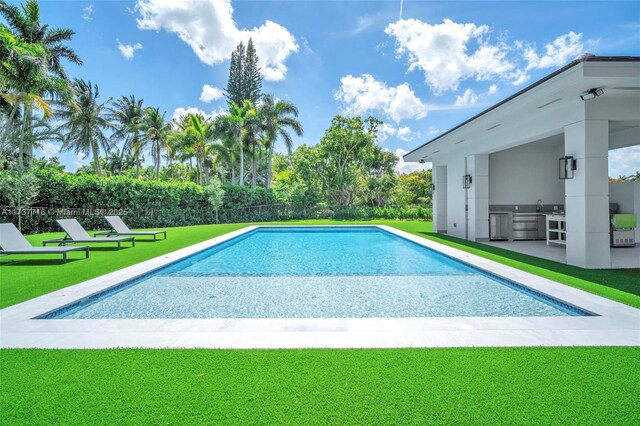 view of swimming pool with area for grilling, a yard, exterior kitchen, and a patio