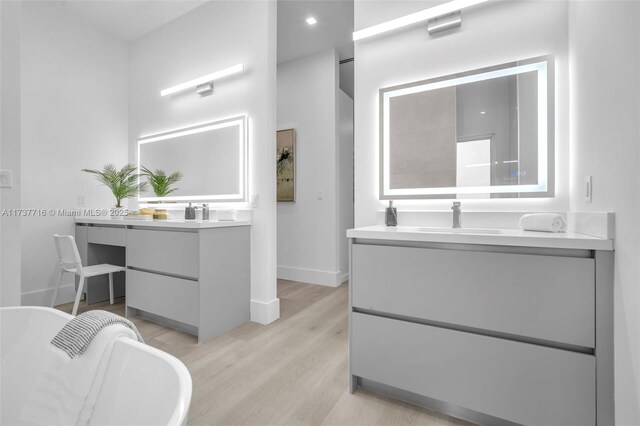 bathroom featuring vanity, wood-type flooring, and a tub to relax in