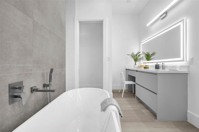 bathroom with hardwood / wood-style flooring, vanity, and a tub