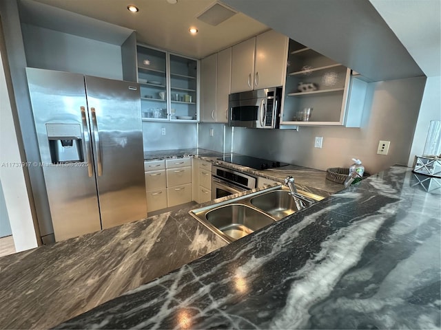 kitchen with appliances with stainless steel finishes, sink, and dark stone counters