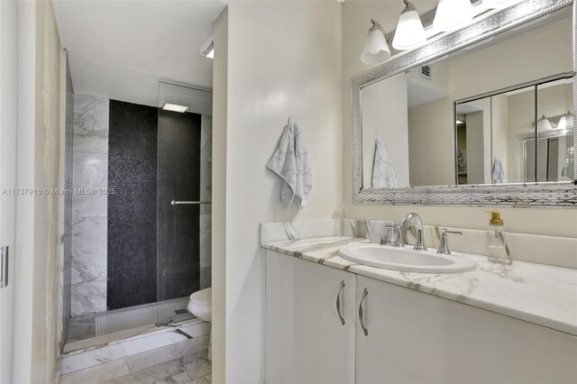 bathroom with vanity, toilet, and tiled shower