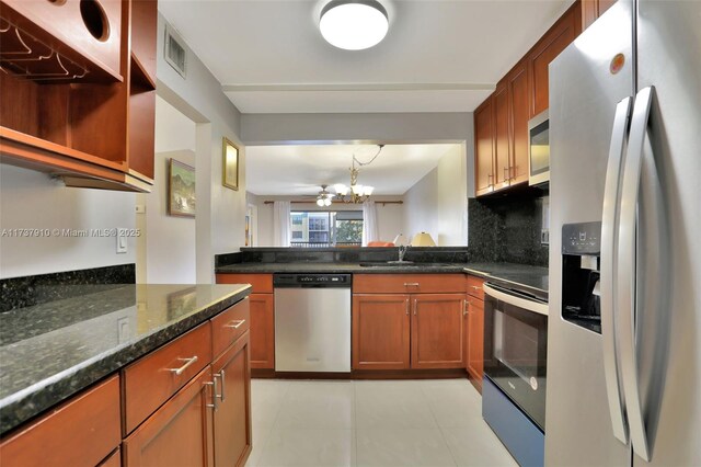 kitchen with pendant lighting, sink, appliances with stainless steel finishes, tasteful backsplash, and dark stone counters