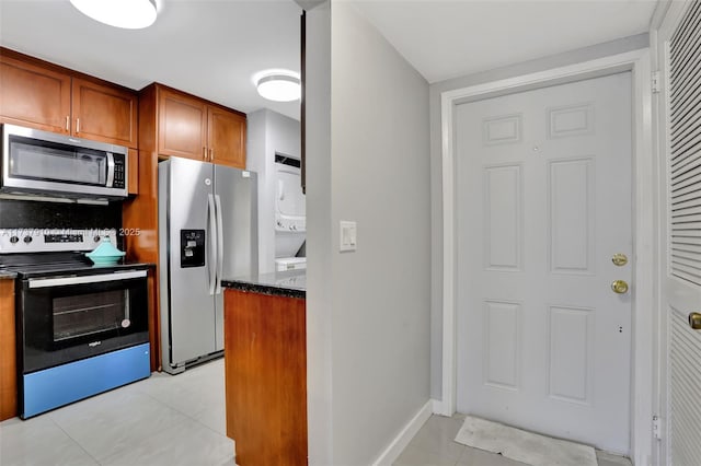 kitchen featuring light tile patterned flooring, appliances with stainless steel finishes, and stacked washer and clothes dryer