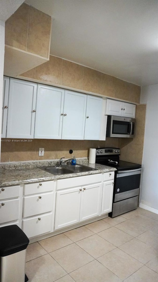 kitchen featuring sink, light tile patterned floors, white cabinets, and appliances with stainless steel finishes