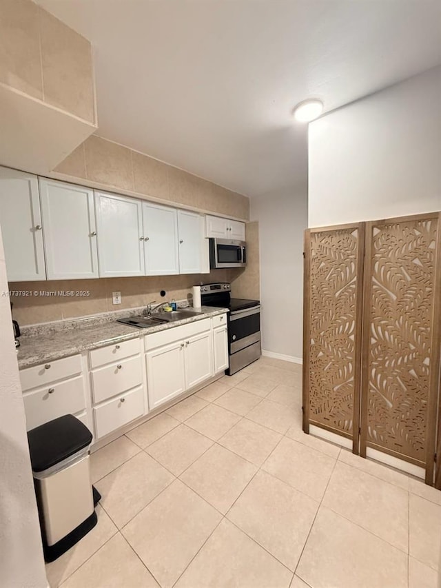 kitchen with light stone counters, stainless steel appliances, and white cabinets