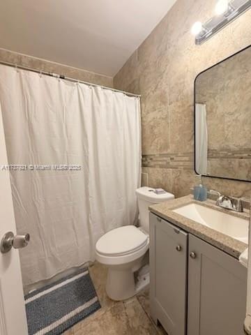 bathroom featuring vanity, toilet, and tile walls