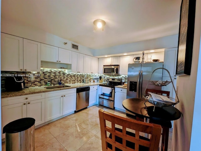 kitchen with sink, backsplash, stainless steel appliances, light stone countertops, and white cabinets