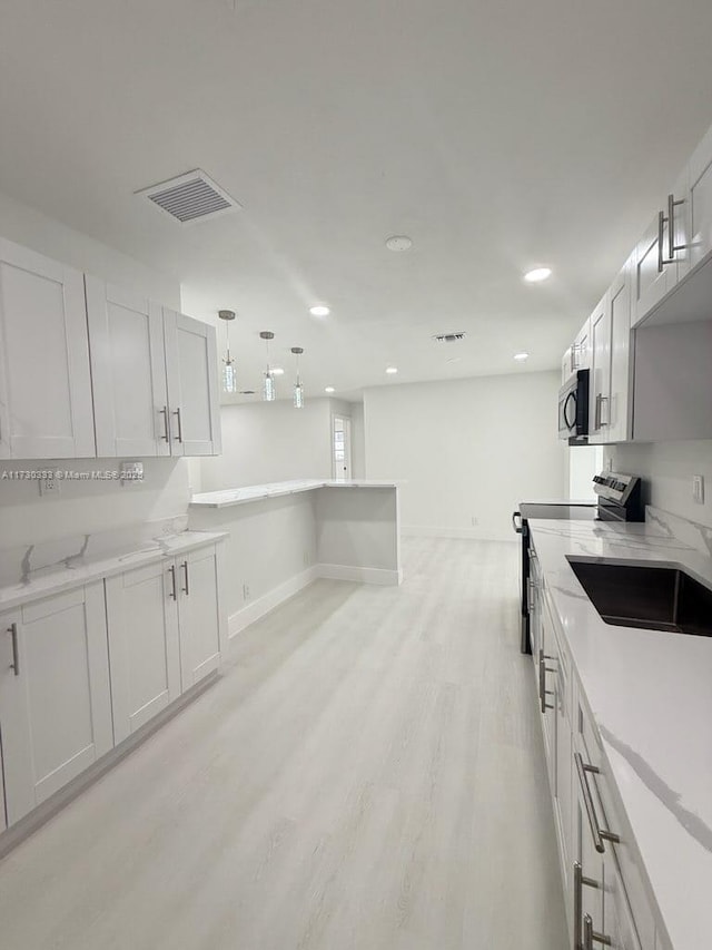 kitchen with visible vents, white cabinets, light wood-style flooring, appliances with stainless steel finishes, and decorative light fixtures