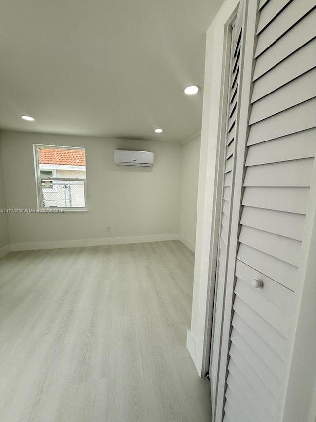 spare room with light wood-style floors, recessed lighting, baseboards, and a wall mounted AC