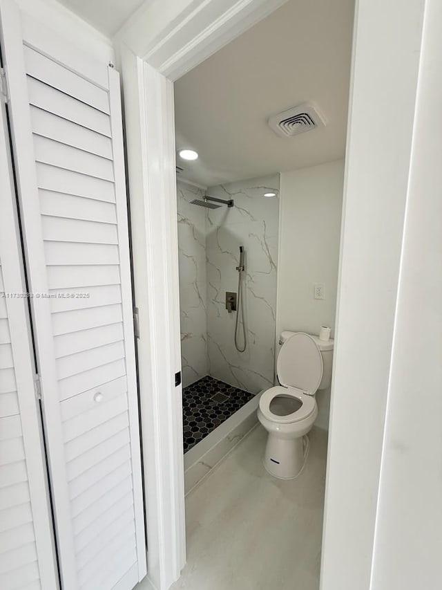 bathroom featuring visible vents, toilet, and a marble finish shower