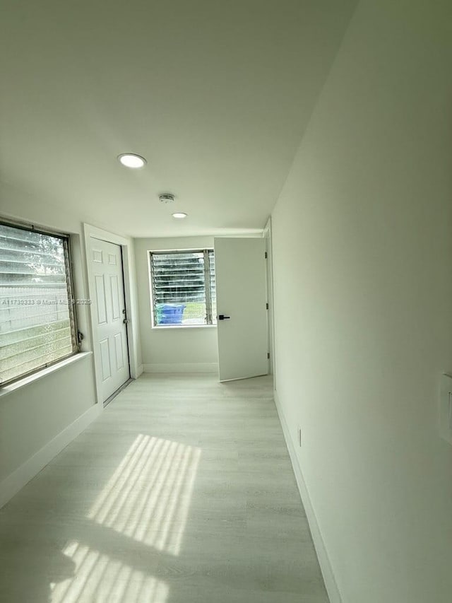 corridor with light wood-style floors, baseboards, and recessed lighting