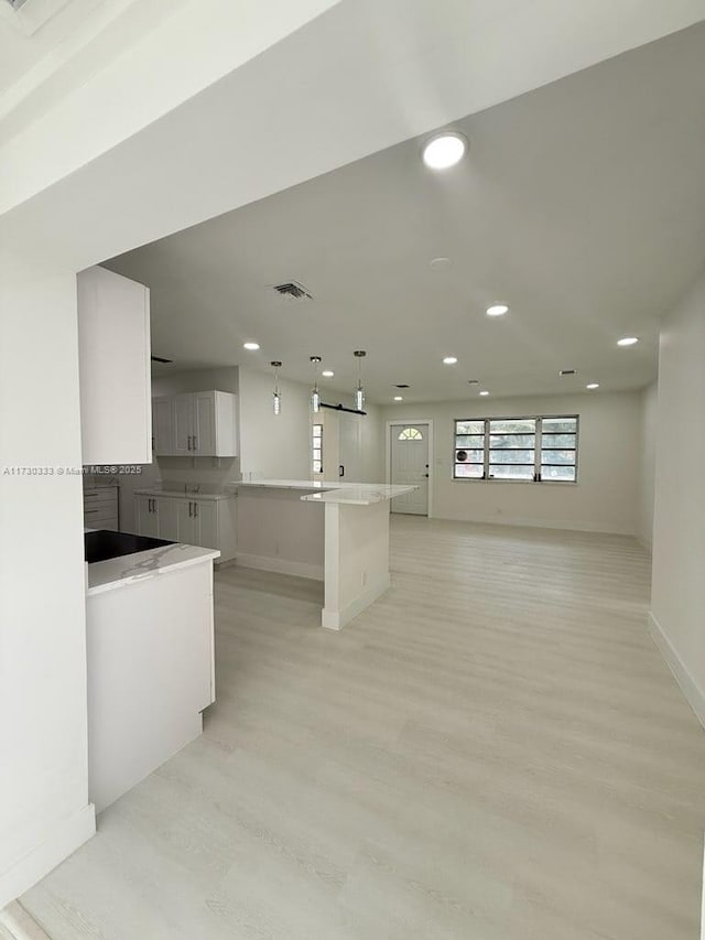 kitchen with light countertops, visible vents, open floor plan, white cabinets, and light wood-type flooring