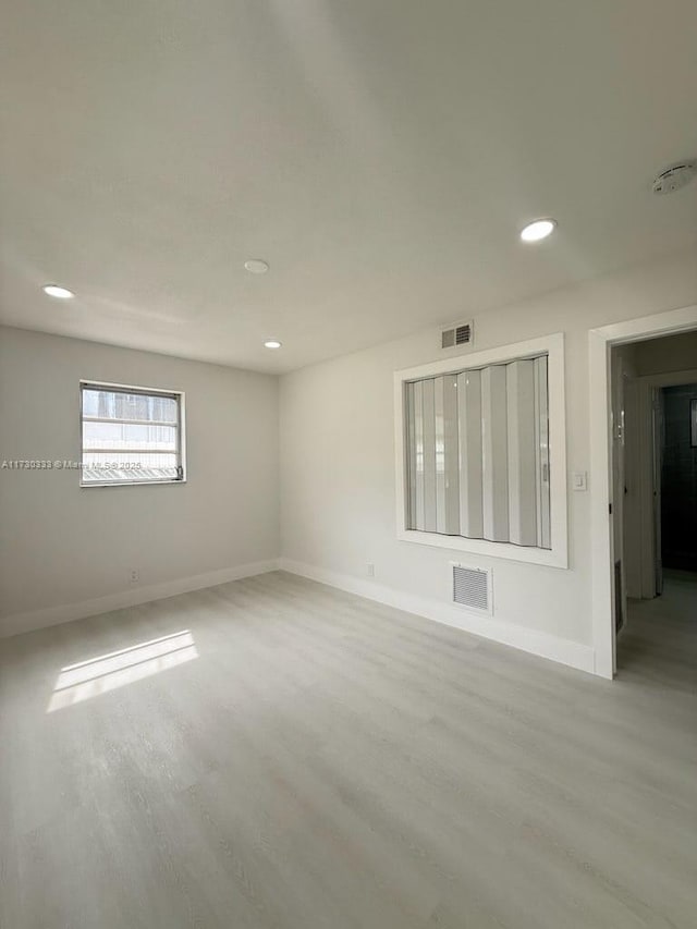 spare room featuring light wood-style flooring, visible vents, and baseboards