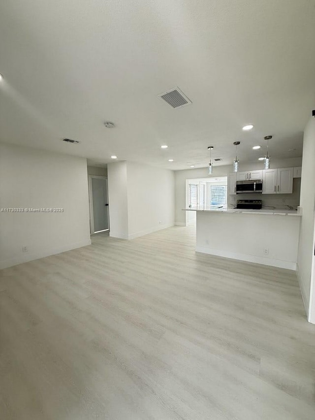 unfurnished living room with light wood-style floors, visible vents, and recessed lighting