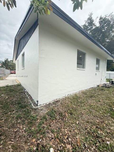 view of side of property with fence and stucco siding