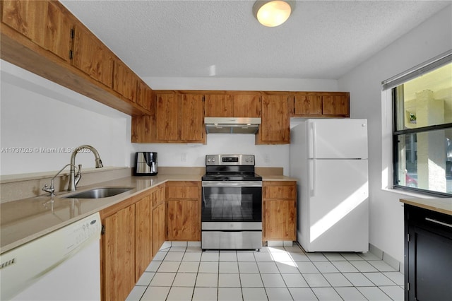 kitchen featuring sink, light tile patterned floors, a textured ceiling, and white appliances