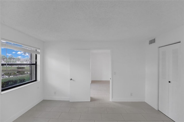 unfurnished room featuring light tile patterned floors and a textured ceiling