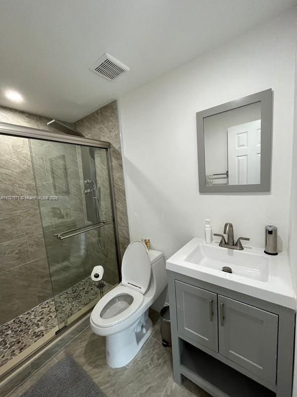 bathroom featuring vanity, an enclosed shower, and toilet