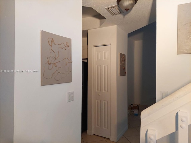 hallway featuring light tile patterned flooring and a textured ceiling