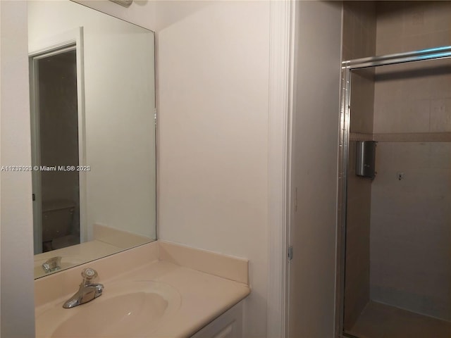 bathroom featuring vanity, an enclosed shower, and toilet