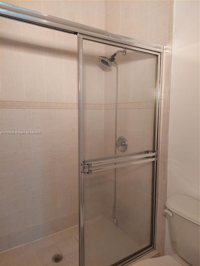 bathroom with a shower with door and toilet