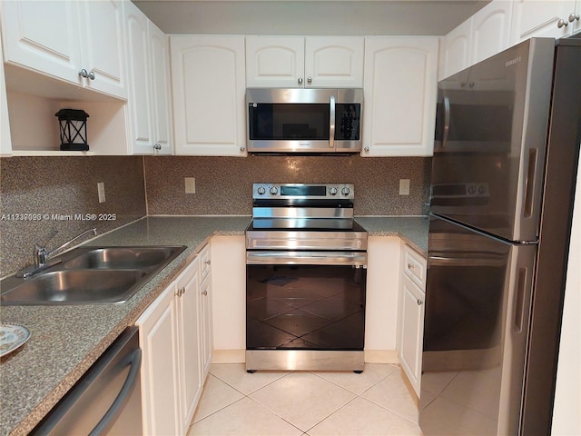 kitchen featuring sink, white cabinetry, light tile patterned floors, stainless steel appliances, and backsplash