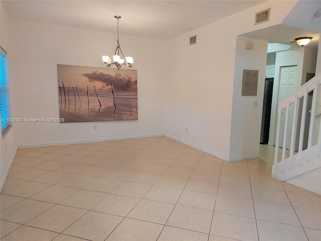 spare room featuring light tile patterned floors and a notable chandelier