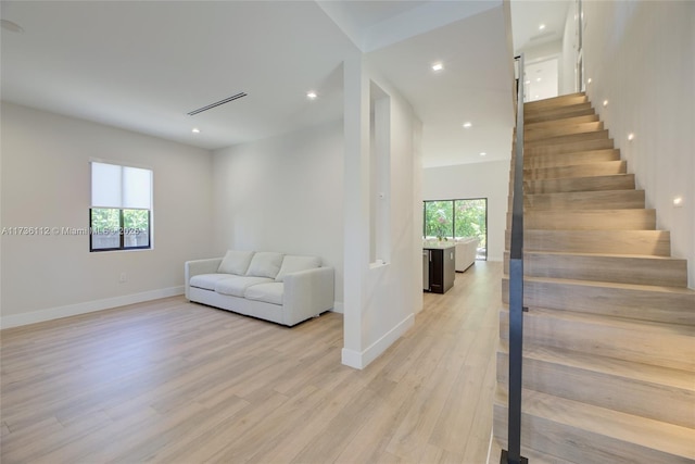 sitting room featuring light wood finished floors, a wealth of natural light, stairs, and baseboards