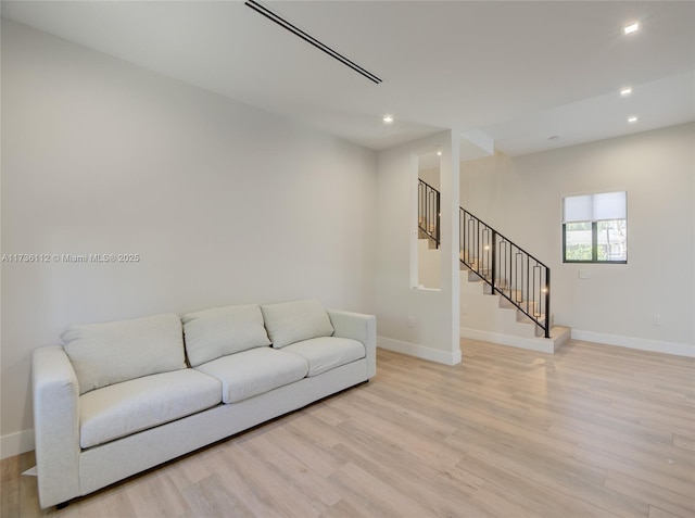 living area with recessed lighting, baseboards, light wood finished floors, and stairs